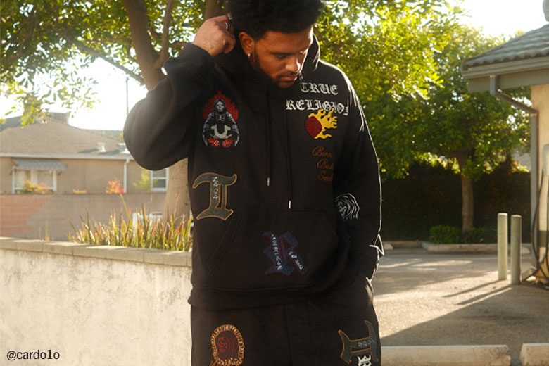 Man wearing true religion black sweatpants and black hoodie with graphics
