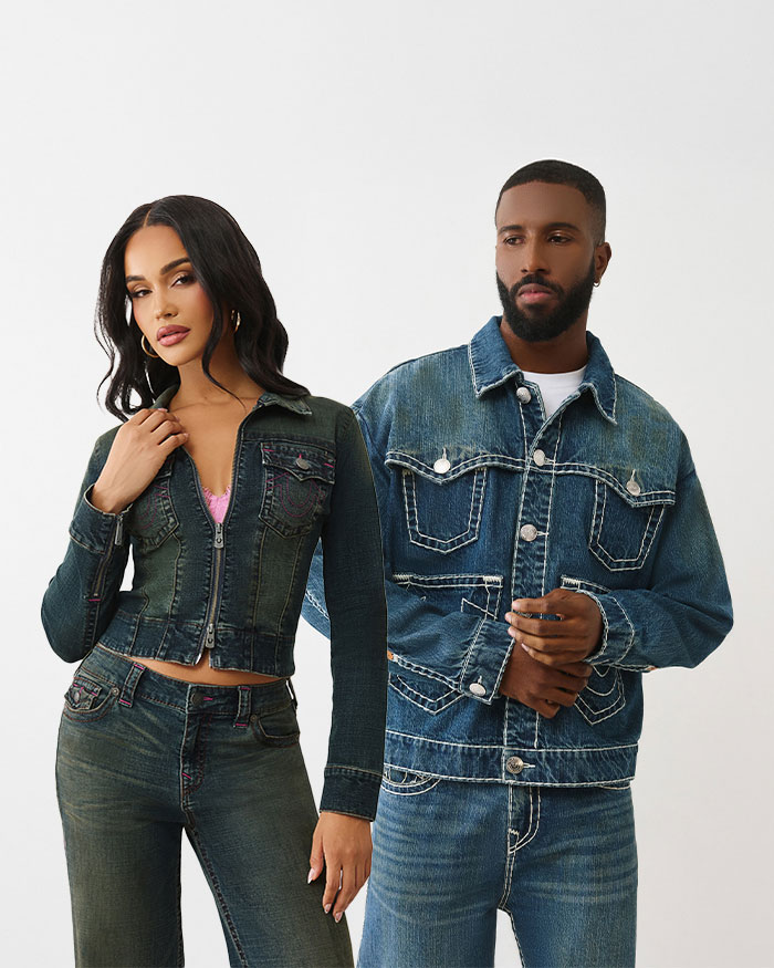 Man and a woman posing, woman wears true religion cropped denim zip up jacket and dark wash jeans, man wears medium wash denim jacket with white stitching and medium wash jeans