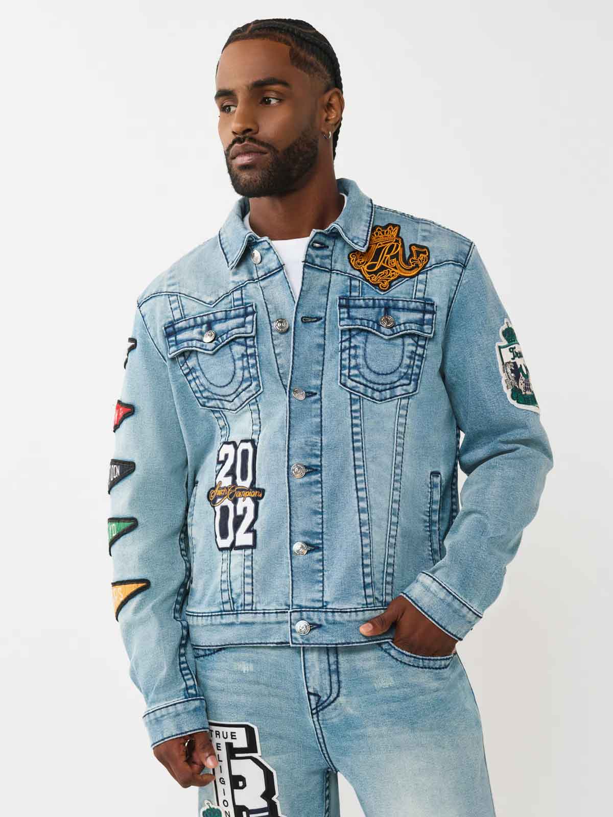 Man wears true religion light wash denim jacket and matching jeans with patch artwork