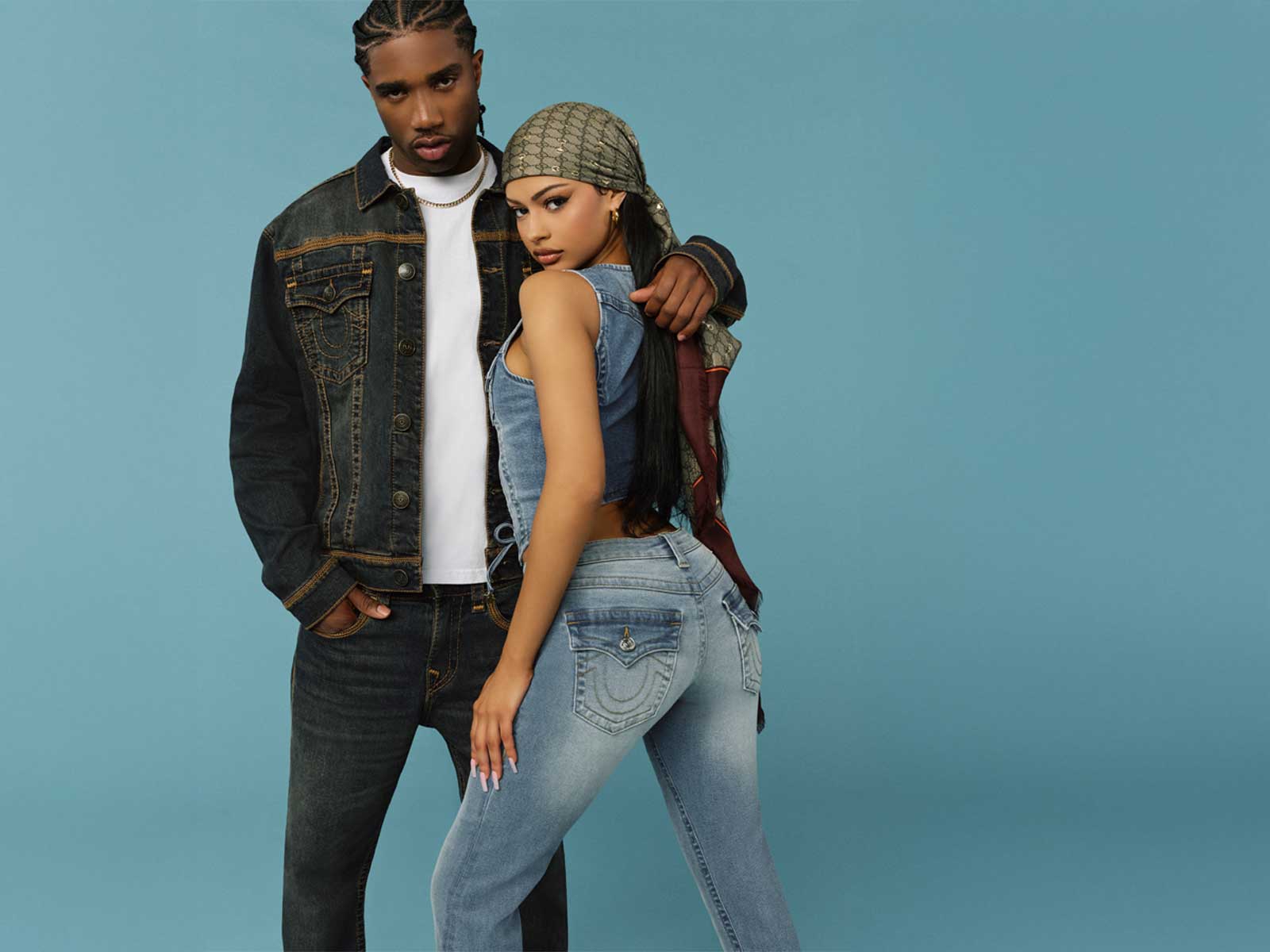 Man wears true religion acid wash jean jacket, white tee shirt, and true religion acid wash straight leg jeans. Woman wears true religion jean vest and true religion jeans