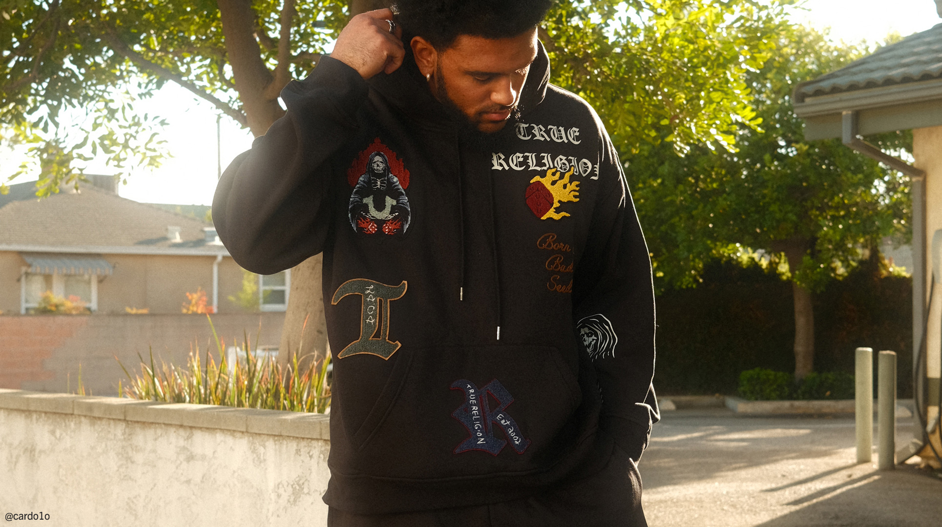 Man wearing true religion black sweatpants and black hoodie with graphics