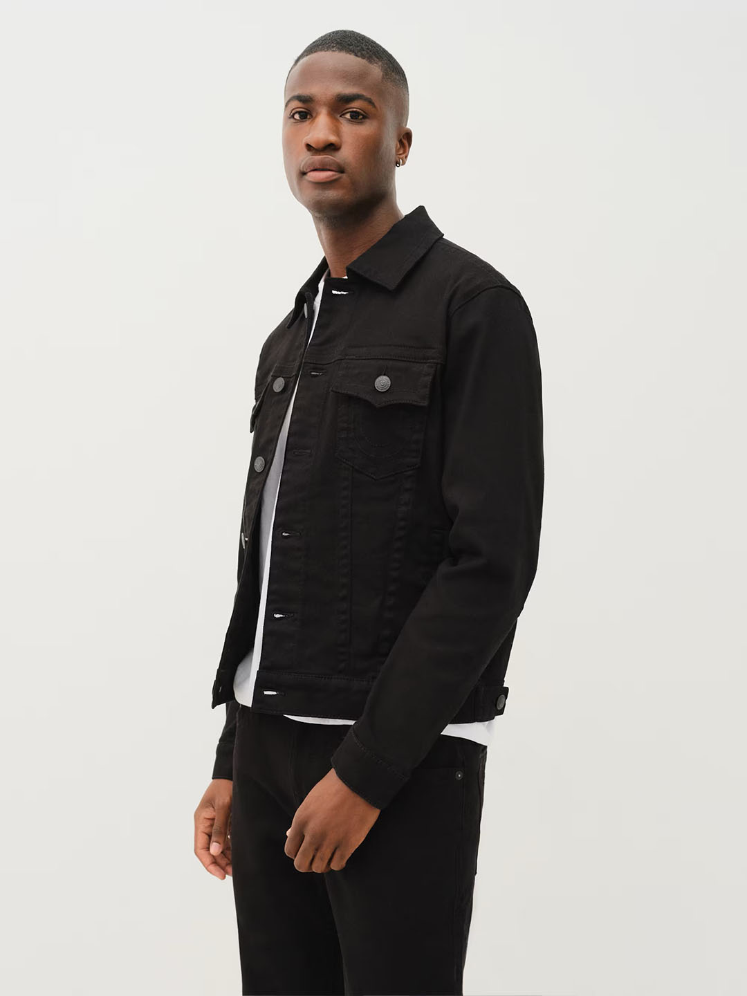 Man wearing a true religion black denim jacket and black jeans