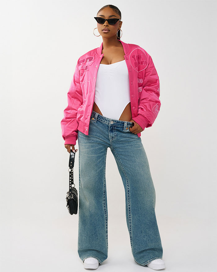 Woman wears a true religion pink oversized bomber jacket with true religion medium wash baggy jeans 