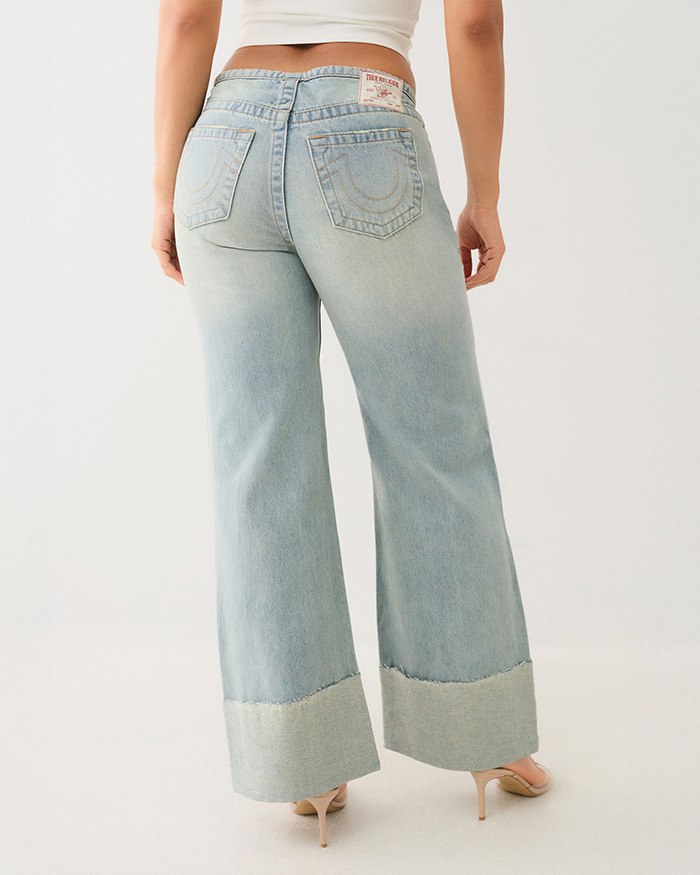 Woman wearing true religion light wash wide leg jeans with a raw hem