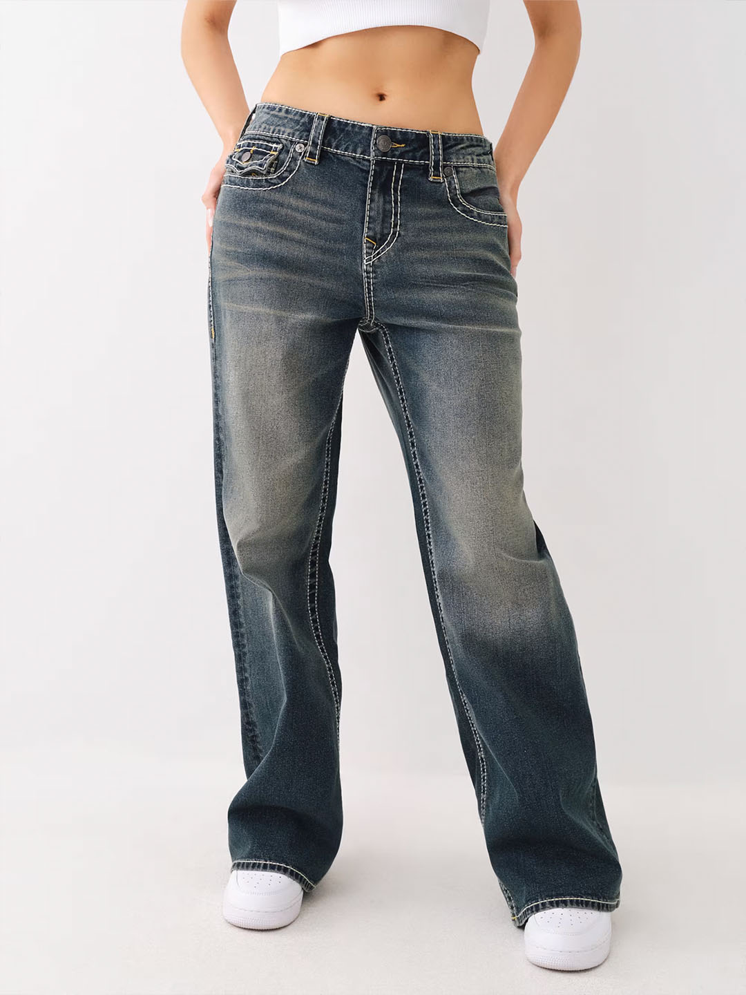 Dark gray wash baggy jeans with white stitching.