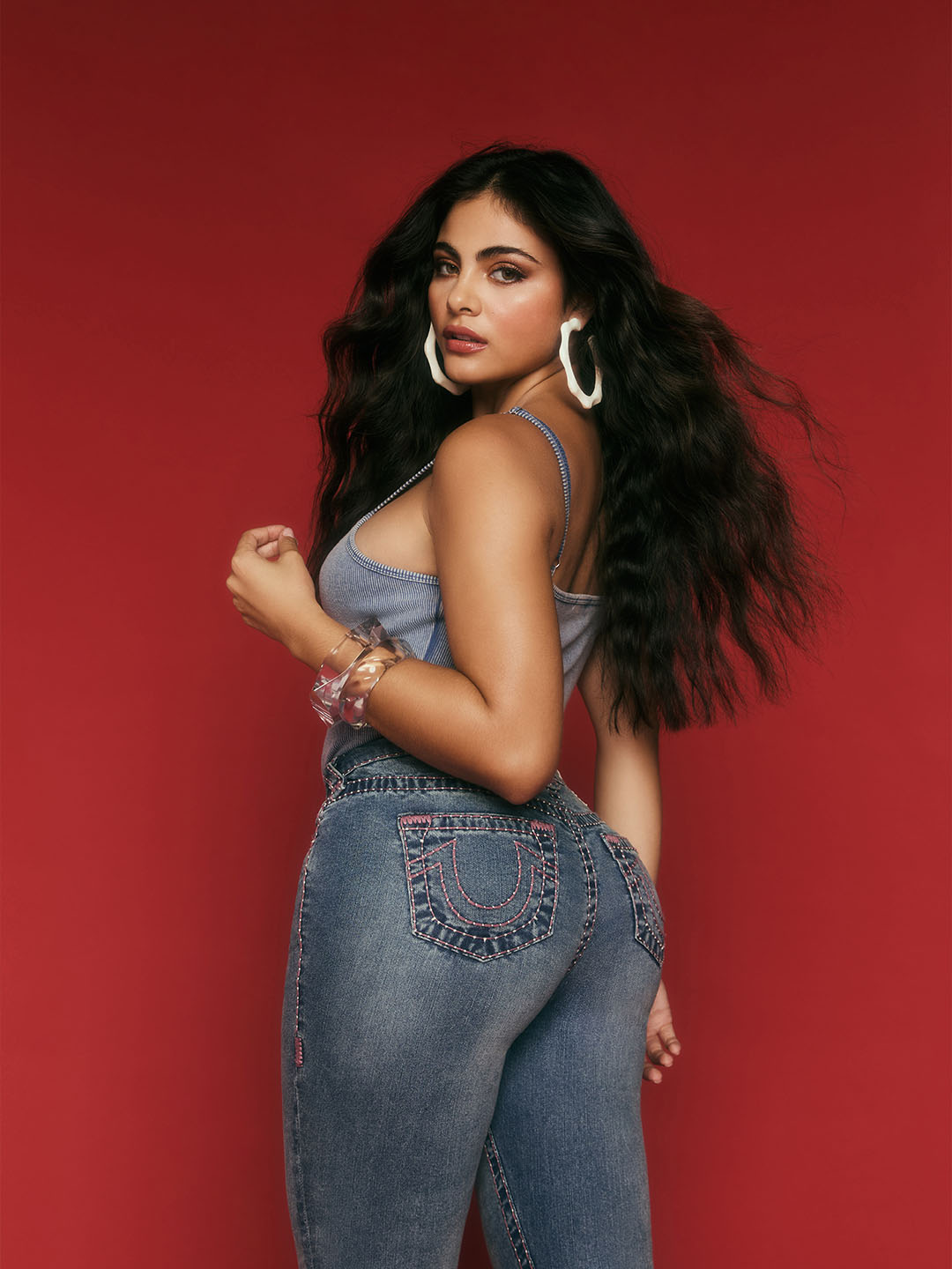 Woman looking backwards wearing true religion light wash jeans with pink stitching.