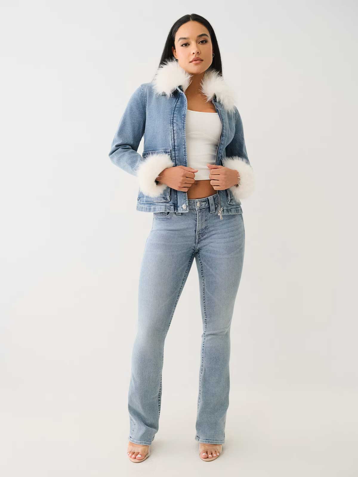 Woman wears true religion denim jacket with fur hood and true religion bootcut jeans 