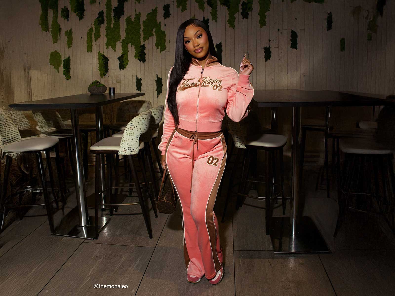 ALT TEXT: Woman wearing a true religion pink sweat set with brown detailing, and pink sneakers