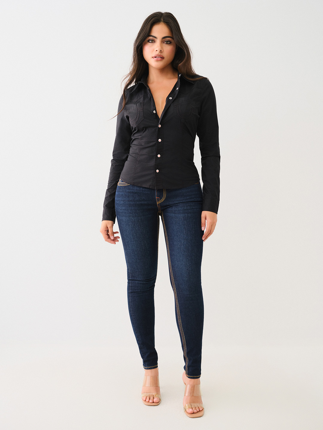 Woman wearing true religion dark wash skinny jeans and a black long-sleeved button down shirt