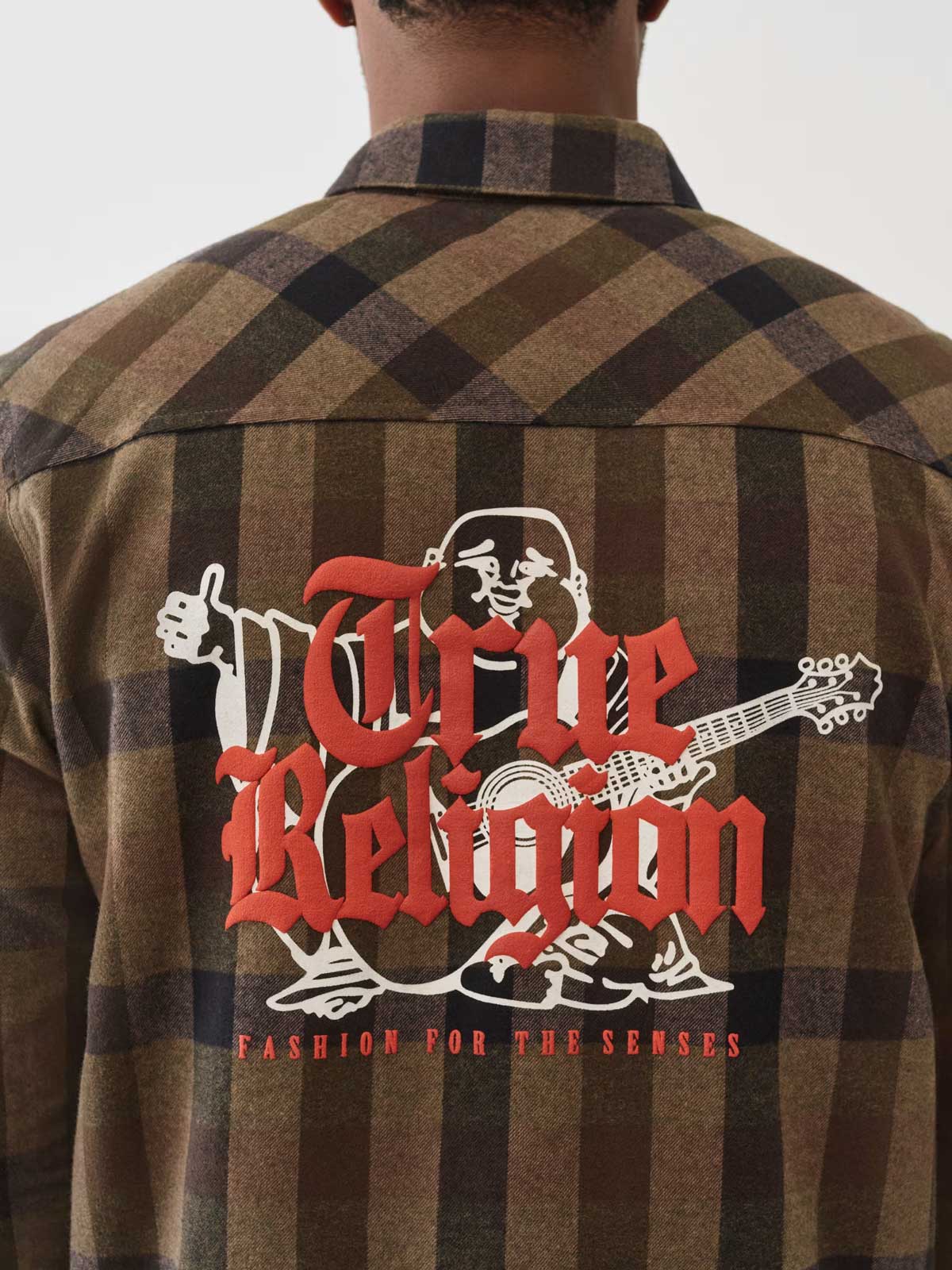 Man wears a flannel jacket with a Buddha picture and the text ‘fashion for the senses