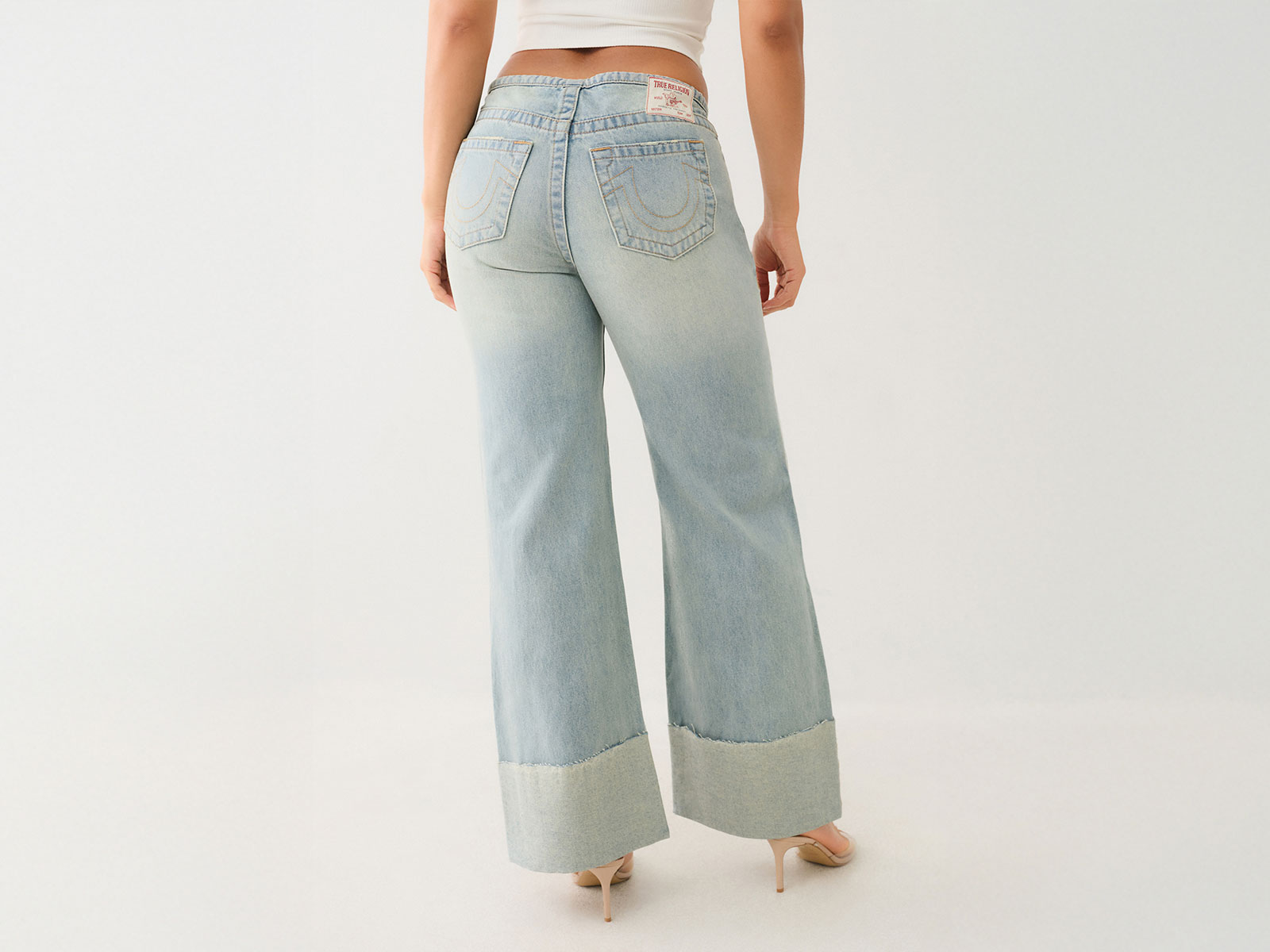 Woman wearing true religion light wash wide leg jeans with a raw hem
