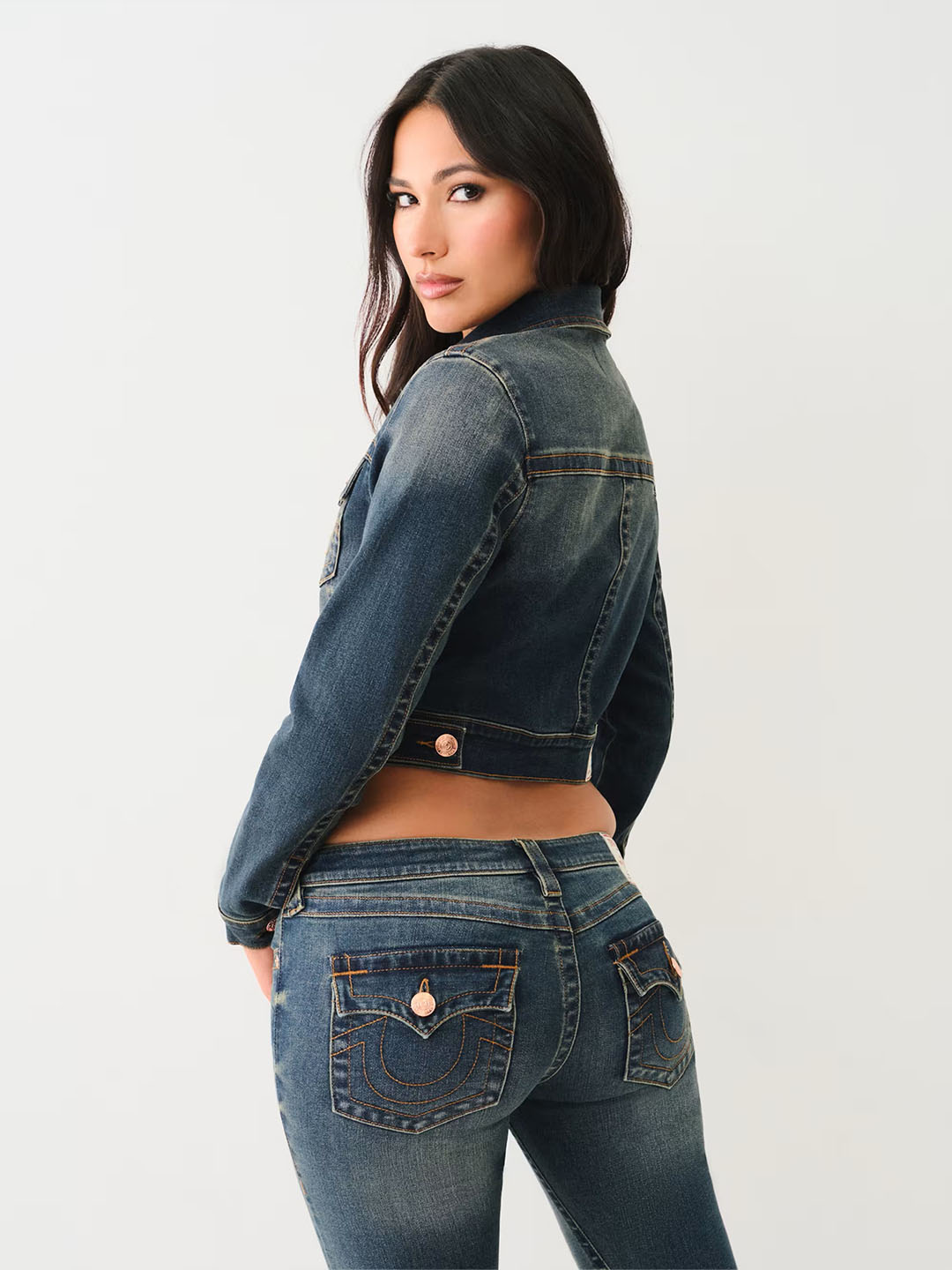Woman wearing true religion dark wash denim jacket and dark wash skinny blue jeans.