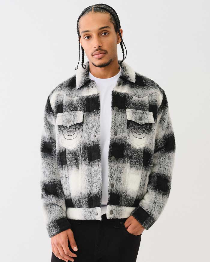 Man poses wearing a true religion black and gray flannel jacket with black true religion jeans